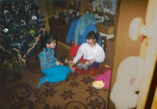 Dziewczynki bawiące się prezentami koło choinki