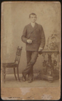 Młody mężczyzna stojący przy stoliku [fotografia]