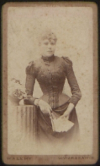 Kobieta stojąca przy stoliku [fotografia]