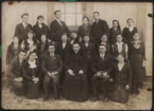 Grupa mieszkańców Paszenek przed kościołem. Władysław Zwierzykowski (ksiądz), Faliks Zieńczuk (organista, siedzi po prawej księdza), Franciszek Krzywda (pierwszy od lewej), Michalina Zieńczuk (stoi pierwsza od prawej), p. Hut (we wzorzystej huście),